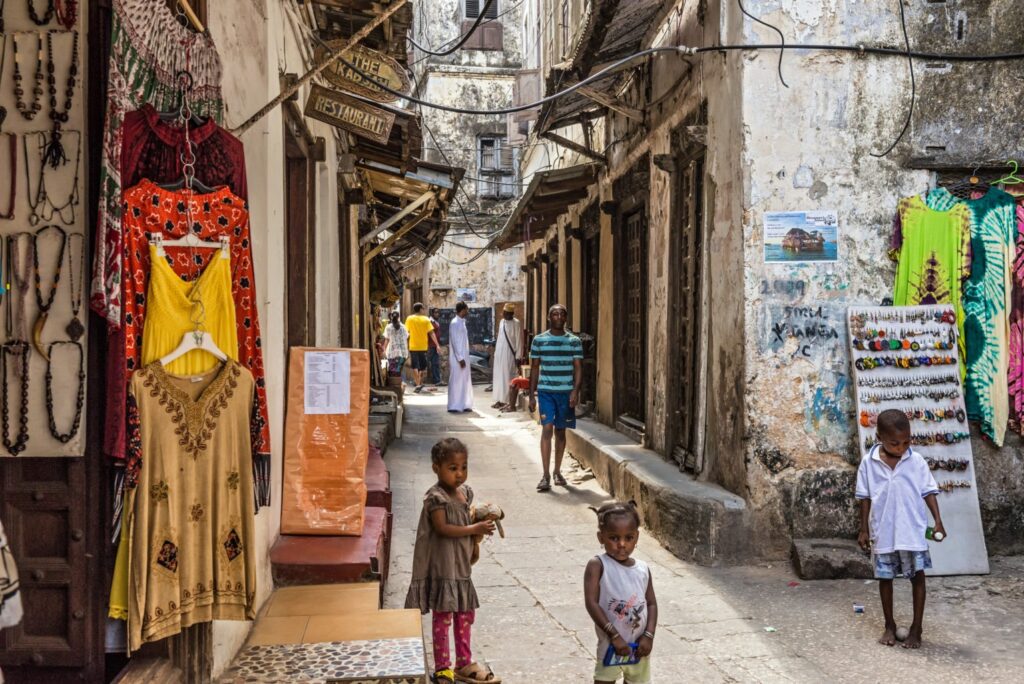 Typische Straße in Stonetown auf Sansibar mit spielenden Kindern, kleinen Geschäften und Restaurants.