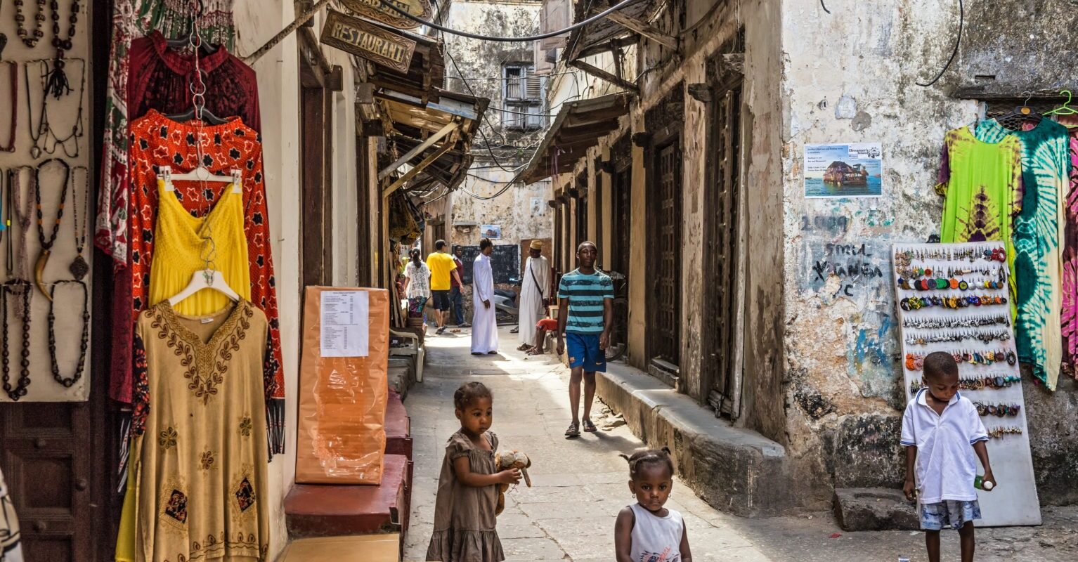 Typische Straße in Stonetown auf Sansibar mit spielenden Kindern, kleinen Geschäften und Restaurants.