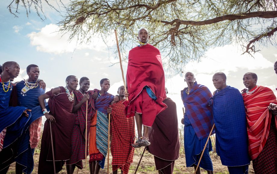 Massai-Krieger in bunten Kleidern springt