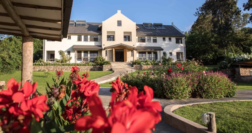 Arusha Villa in Tanzania Hauptgebäude mit Garten und roten Blumen im Vordergrund